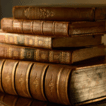 5 grossi libri antichi poggiati su un tavolo in legno