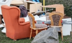 vari mobili usati tra cui vecchie sedie una poltrona rossa e altro materiali posizionati in uno spazio aperto